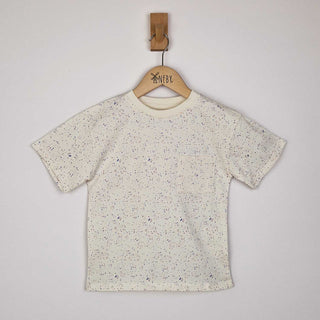 Flat lay of an ecru children's paint splat t-shirt, front view. The t-shirt features a scattered paint splatter pattern in soft pastel and earthy tones, adding a creative and playful look.