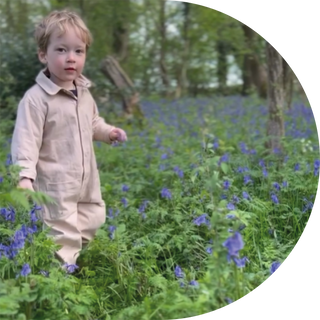 Boy wearing Aneby beige boilersuit in bluebell field