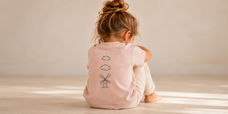 Young child sitting quietly after nursery wearing a pink Aneby T-shirt
