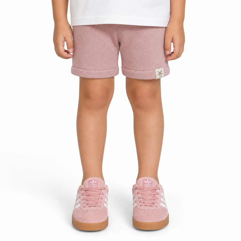 A child wearing dusty pink shorts with rolled cuffs and matching pink trainers, shown from the waist down on a white background.