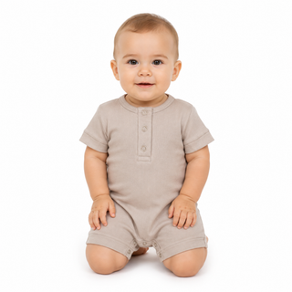 A baby wearing a short-sleeve romper in a light beige colour, kneeling on a white background.