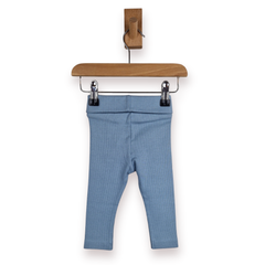 Dusty blue baby leggings hanging from a wooden hanger with metal clips against a plain white background.
