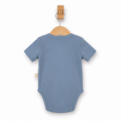 A light blue short-sleeve baby bodysuit shown from the back, hanging on a wooden hanger from a wooden wall hook against a plain white background.