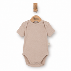 Beige baby bodysuit on a wooden hanger hanging on a wooden hook with a plain white background.