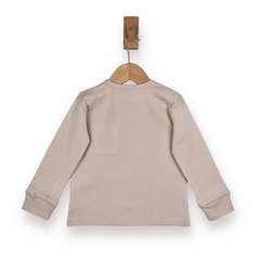 A light beige long-sleeve knit top hanging on a wooden hanger with a wooden peg, shown from the back against a white background.