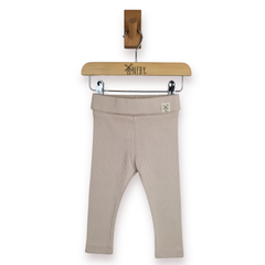 A pair of ribbed knit toddler leggings in a light taupe-beige colour, hanging from a wooden hanger against a plain white background.