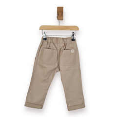 A pair of beige toddler pants shown from the back, hanging from a wooden hanger with metal clips against a clean white background.