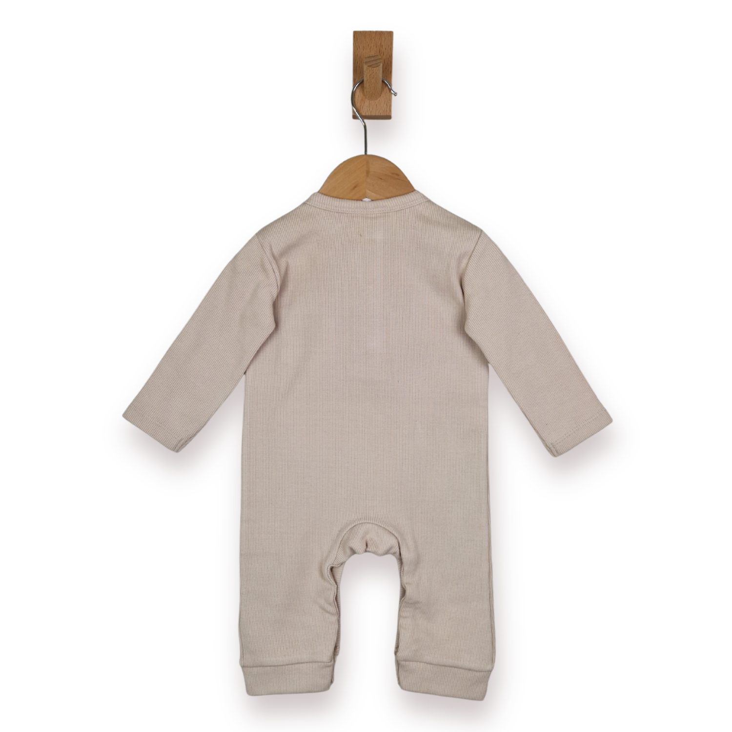 A light beige long-sleeve baby romper hanging on a wooden hanger from a wall hook, shown from the back against a plain white background.