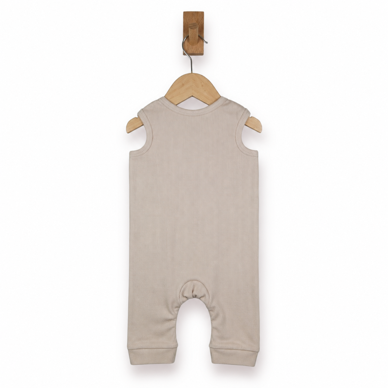 A sleeveless baby romper in a light oatmeal beige color, hanging on a wooden hanger from a wall hook against a plain white background.