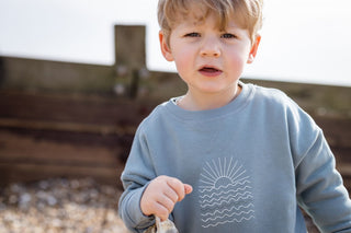 Close up image of an Aneby model wearing a jumper with a sunrise design