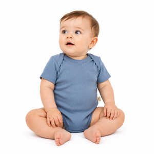 A baby sitting cross-legged wearing a short-sleeve blue bodysuit, photographed against a clean white background.