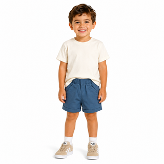 Blue chino shorts modelled by a young boy wearing a white t-shirt and Adidas trainers, against a white background. 