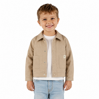 A young boy smiling, wearing a light oat jacket over a white t-shirt and light blue jeans, photographed against a solid white background.