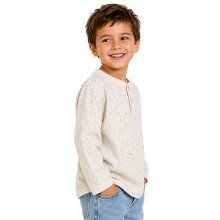 Child wearing a light-coloured ecru long sleeve t shirt and jeans on a white background