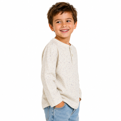 Child wearing a light-coloured ecru long sleeve t shirt and jeans on a white background