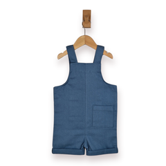 A baby romper in a medium blue denim-like fabric, hanging from a wooden hanger on a wall hook against a white background.