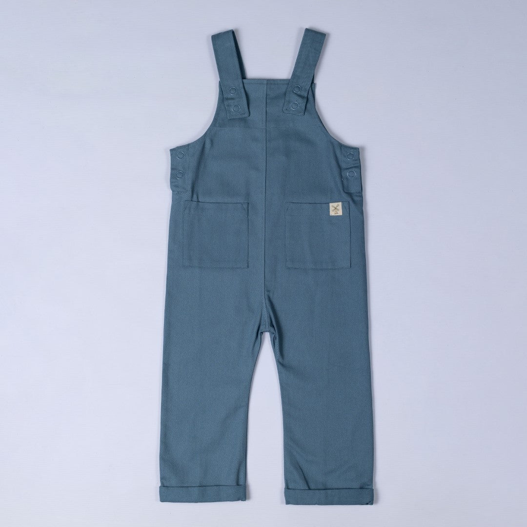 Steel blue dungarees with shoulder straps, patch pockets, dyed to match poppers and rolled hem