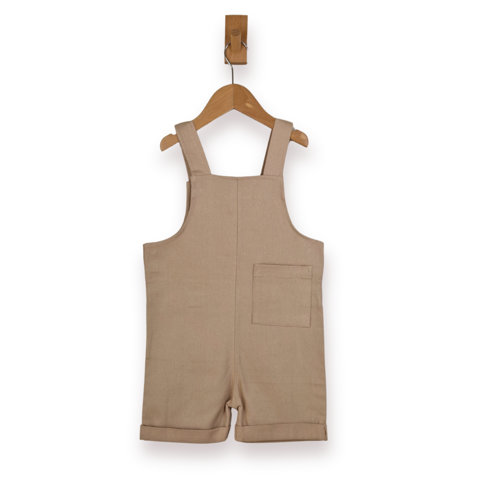 Beige dungaree shorts hanging on a wooden hanger against a white background.