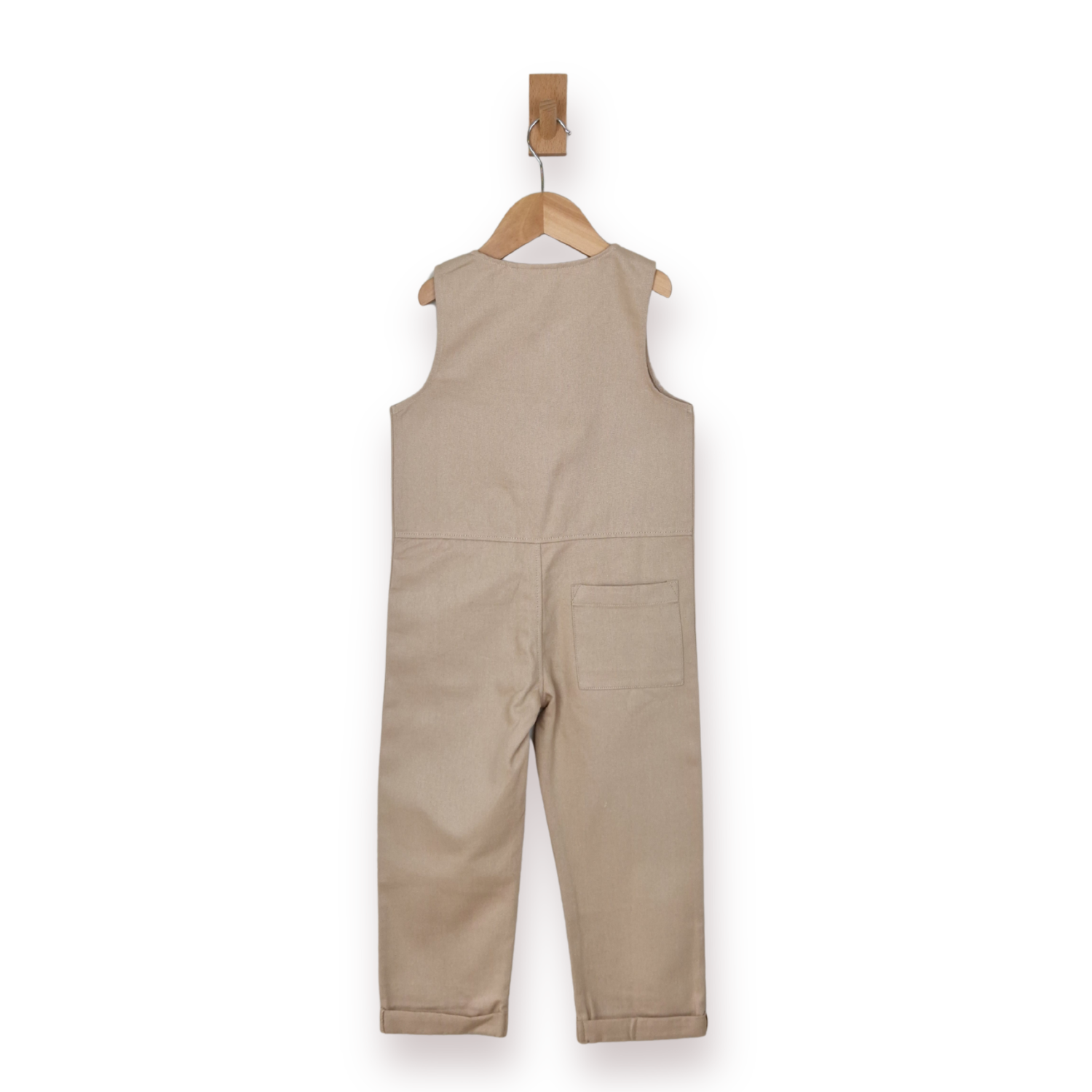 A sleeveless beige children's jumpsuit or romper hanging from a wooden hanger against a plain white background.