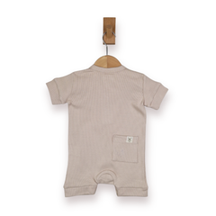 A light beige short-sleeve baby romper hanging on a wooden hanger from a brown wall hook, shown against a plain white background.