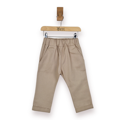 A pair of toddler's beige trousers with an elastic waistband and side pockets, hanging from a wooden hanger against a plain white background.
