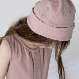 Aneby model wearing a pink beanie hat with long brown hair sweeping down