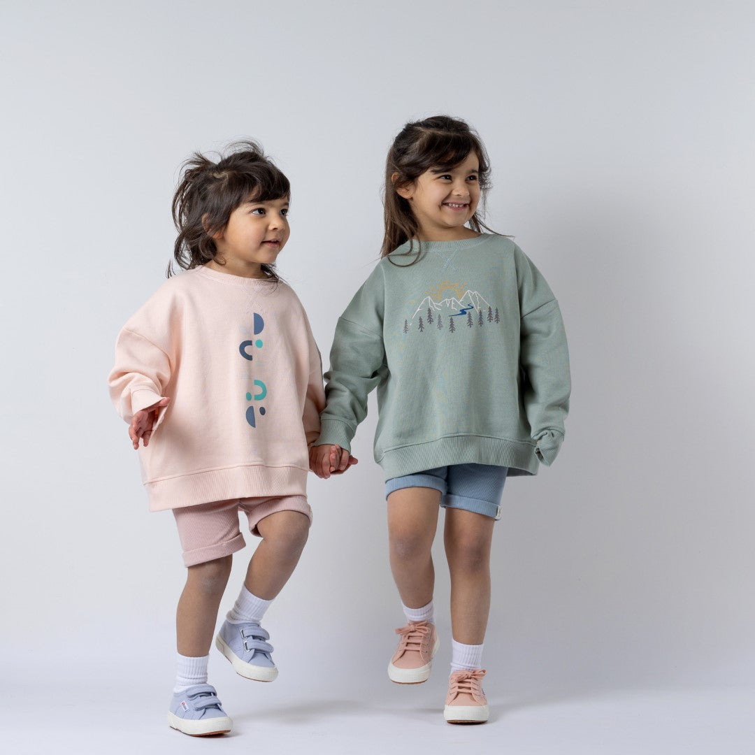 Two young models holding hands whilst wearing Aneby sweatshirts featuring the moon and camping designs