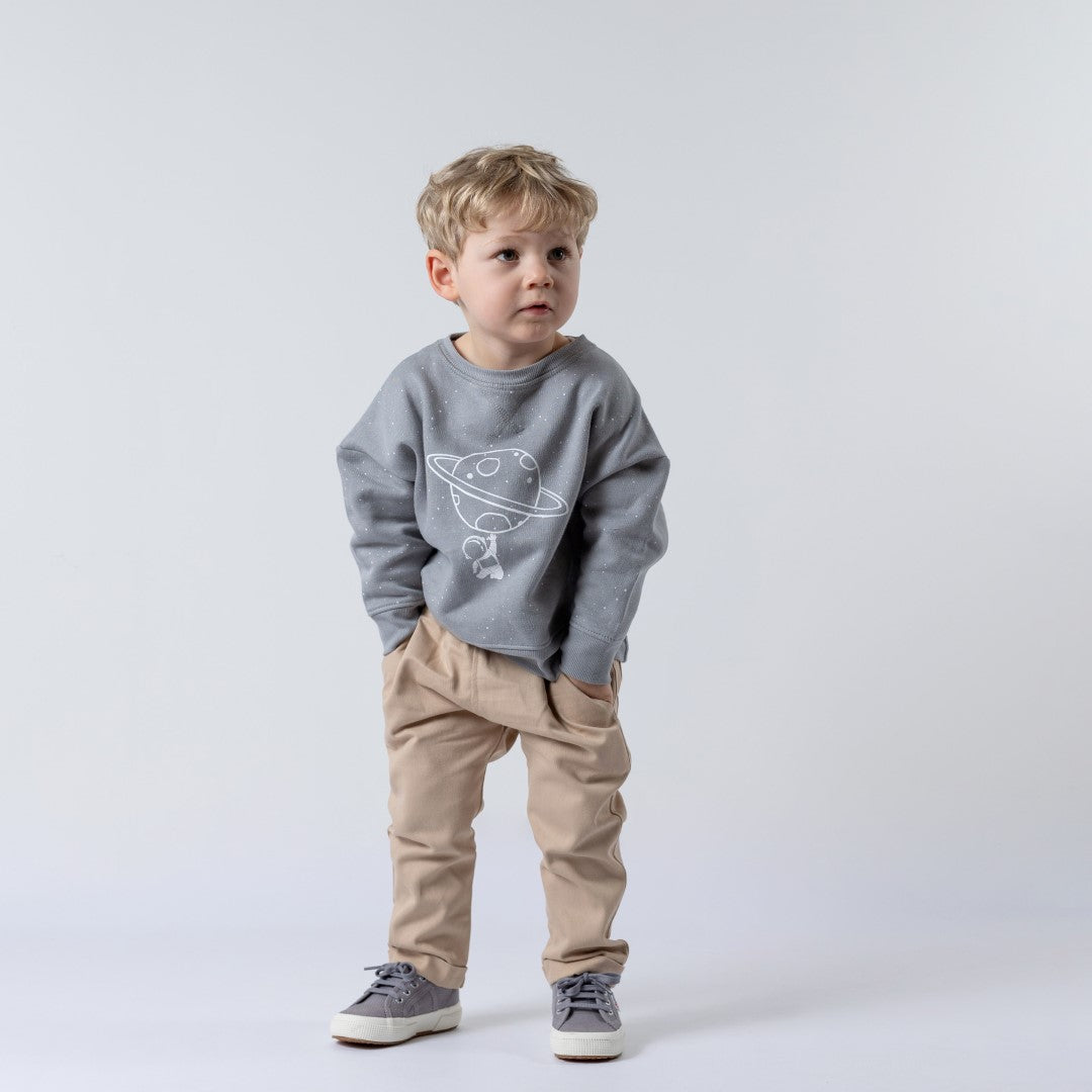 Blonde haired boy wearing grey space jumper with beige chinos