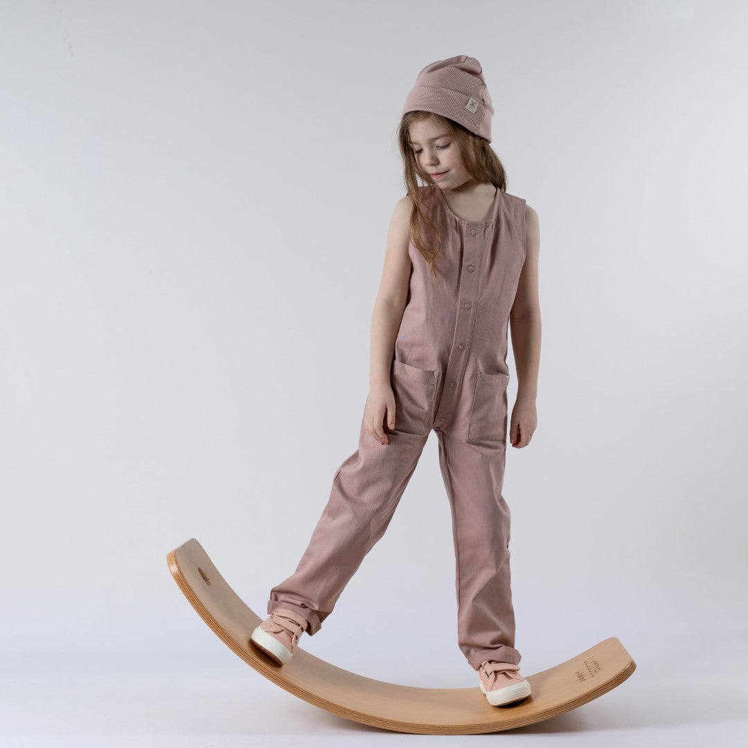Aneby model wearing a pink jumpsuit standing on a wooden wobble board