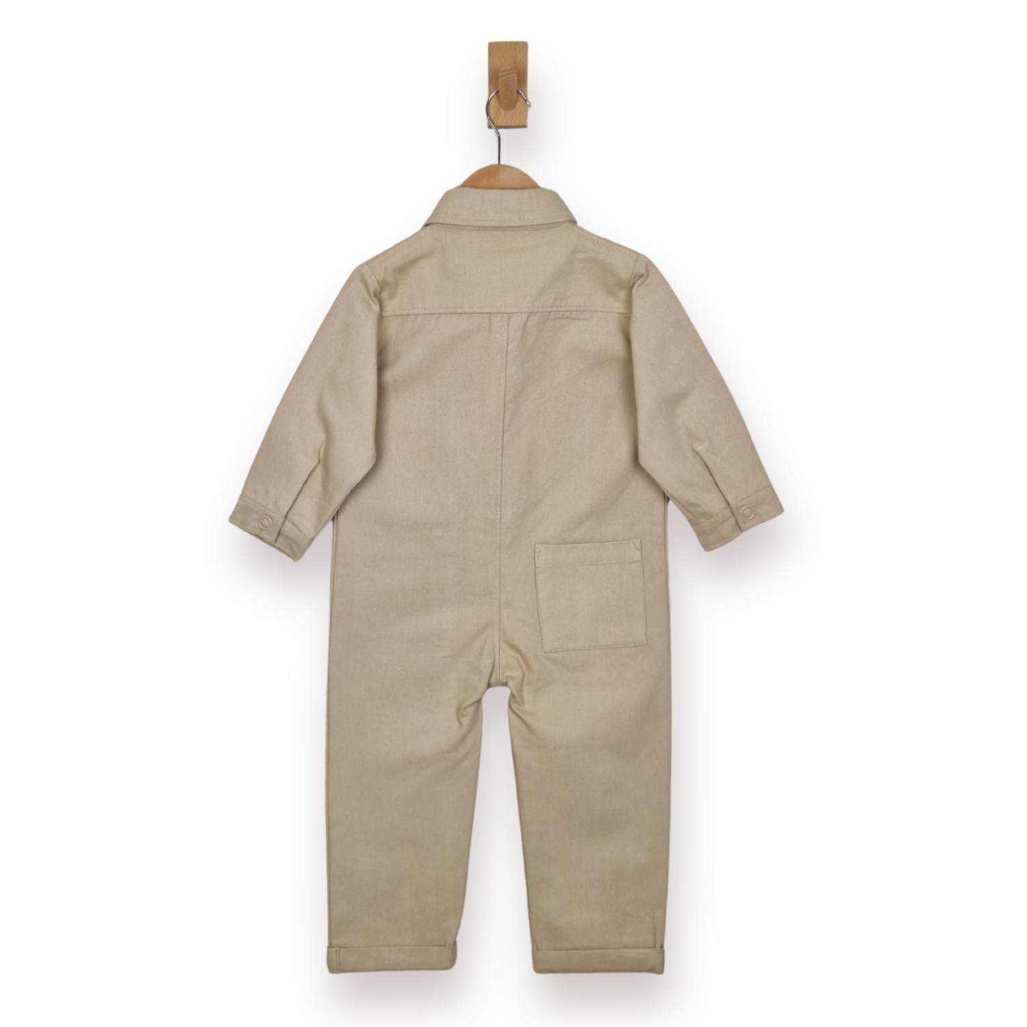 A light beige children's jumpsuit or boilersuit hanging on a wooden hanger against a plain white background, shown from the back.