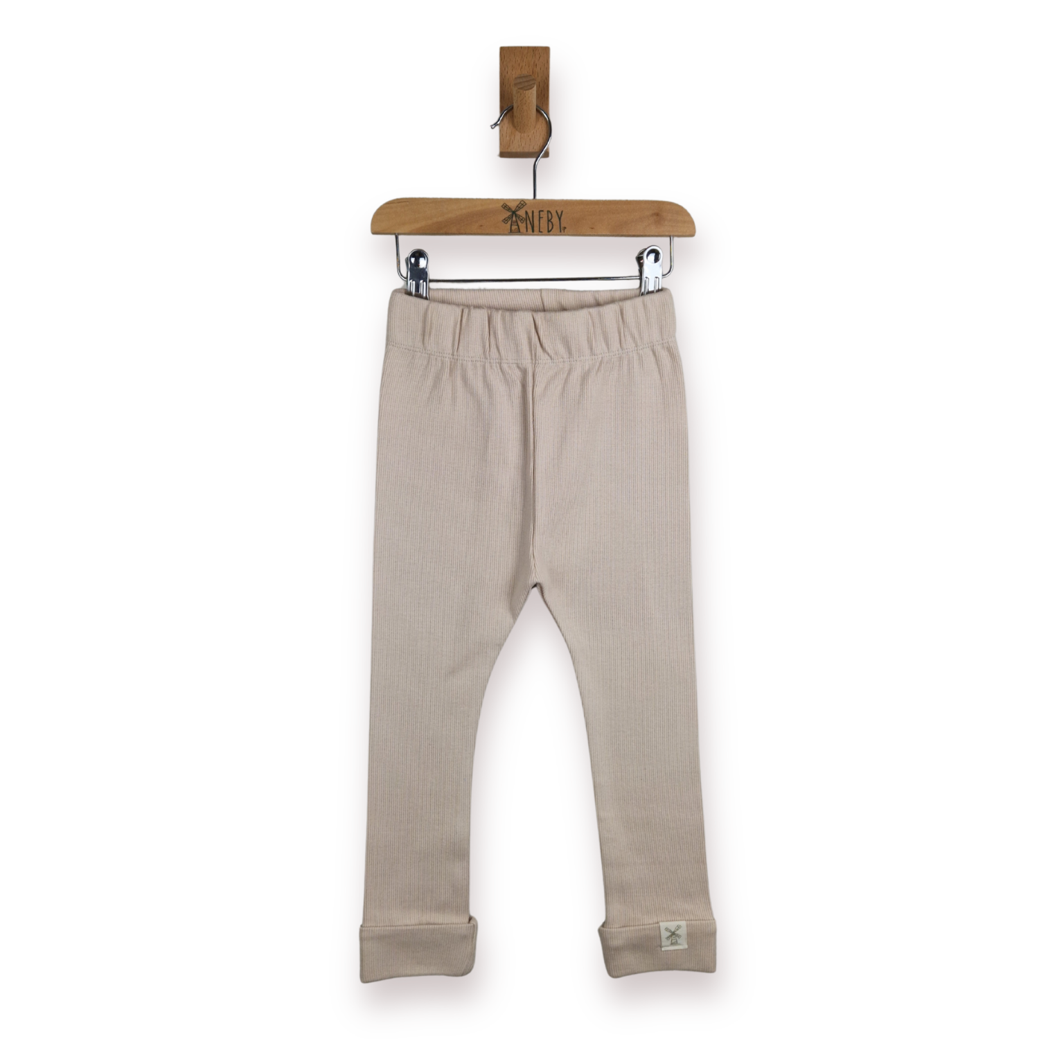 A pair of light beige toddler leggings hanging from a wooden hanger on a white background.