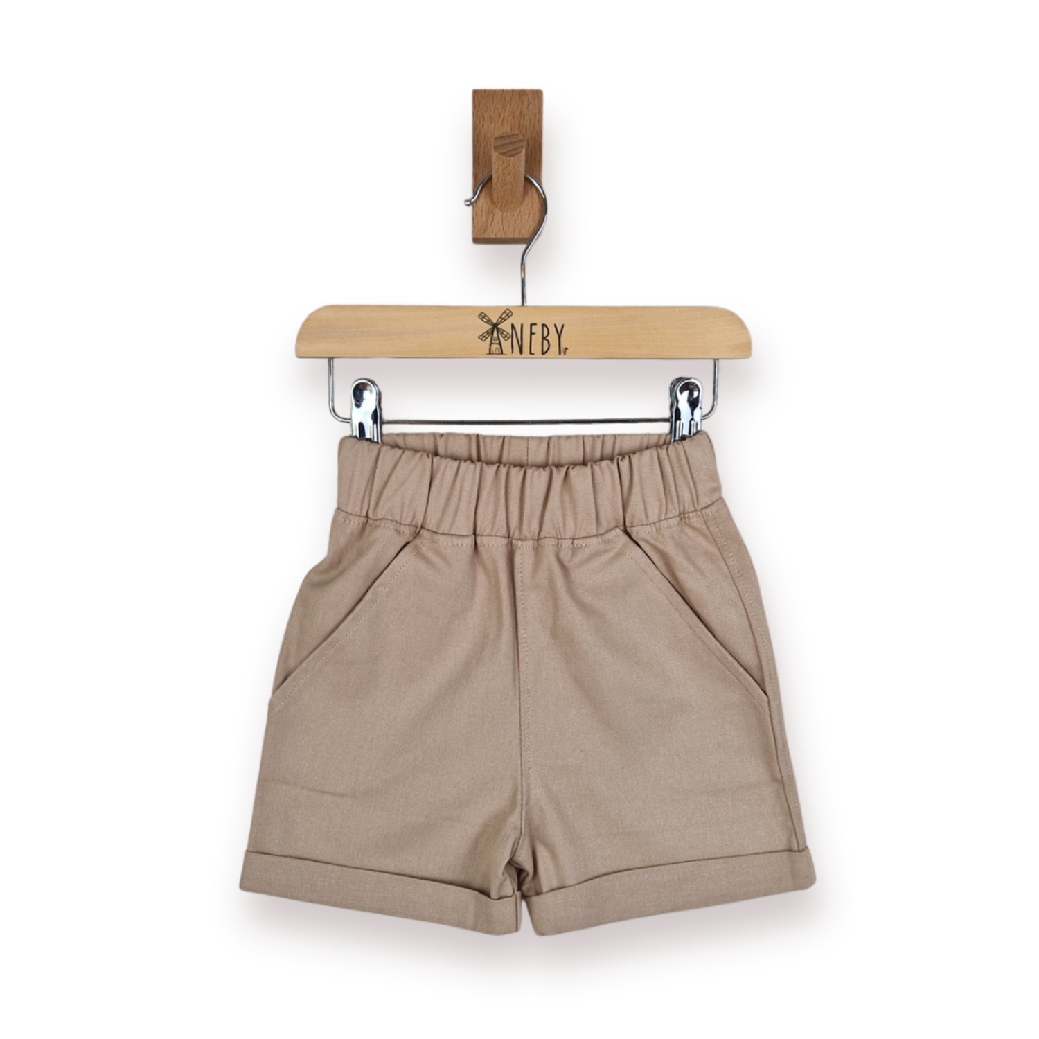 A pair of beige elastic-waist shorts with side pockets, hanging from a wooden hanger branded 'ANEBY' on a white background.