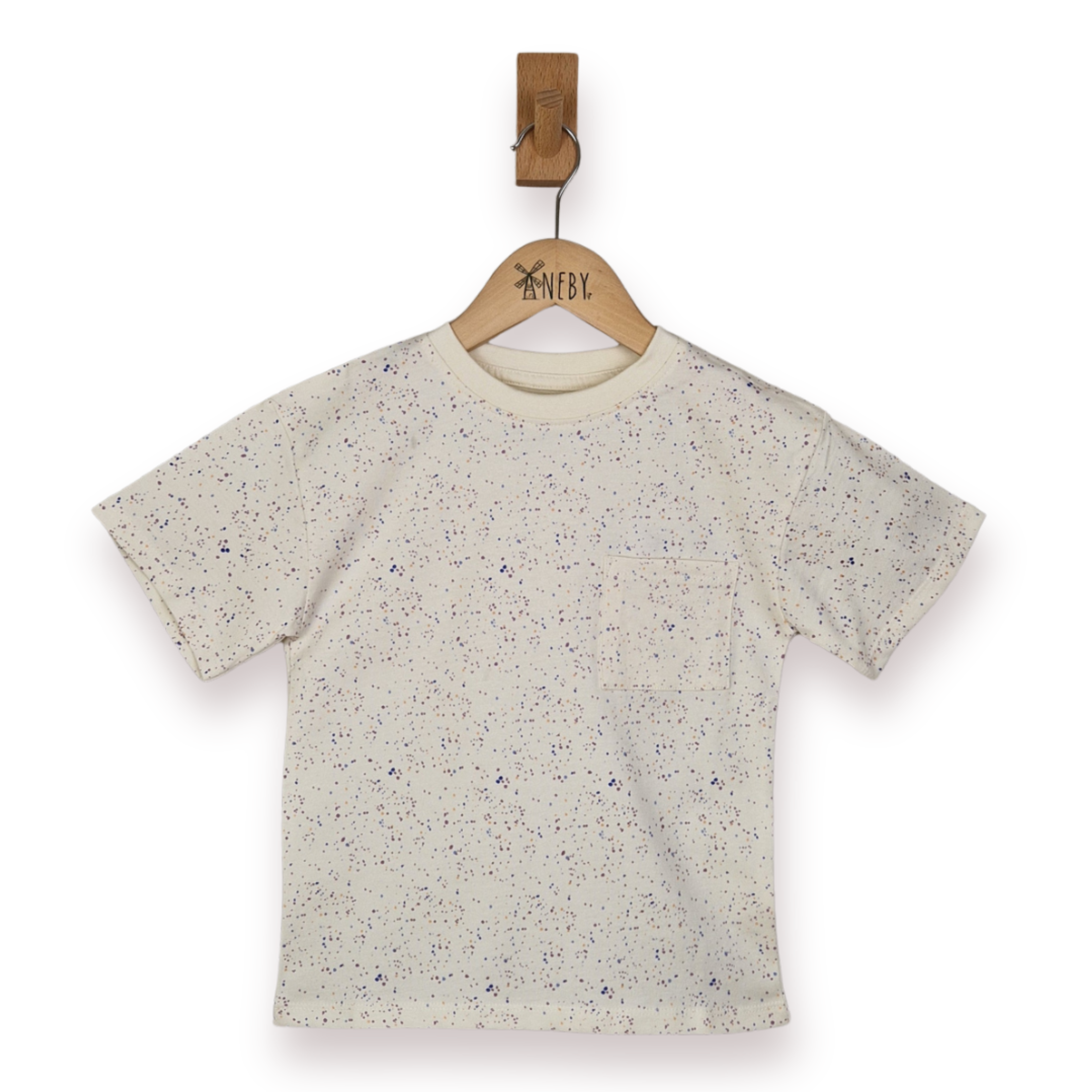 Kids ecru t-shirt with speckled pastel print and patch pocket on a wooden hanger against a white background