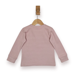 A dusty pink long-sleeve ribbed knit top shown from the back, hanging on a wooden hanger with a wooden peg against a plain white background.