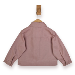 A dusty rose pink children's jacket shown from the back, hanging on a wooden hanger from a wall hook against a white background.