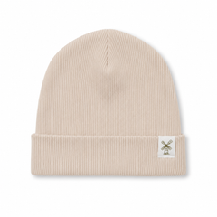 A ribbed knit beanie hat in a light beige or cream colour, featuring a small white square patch on the folded cuff with a windmill graphic.