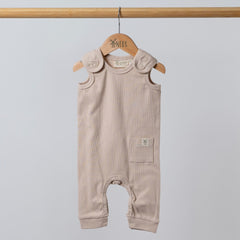 Beige baby romper hanging from wooden hanger with dyed to match poppers