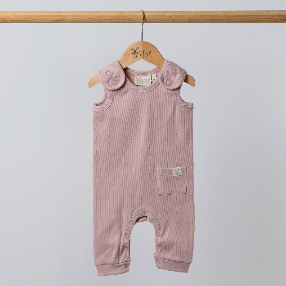 Pink baby romper with shoulder straps and dyed to match poppers hanging from wooden pole