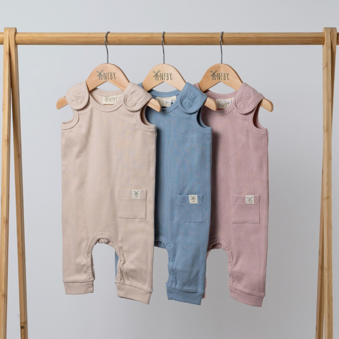 Matching baby rompers in beige, blue and pink on hangers
