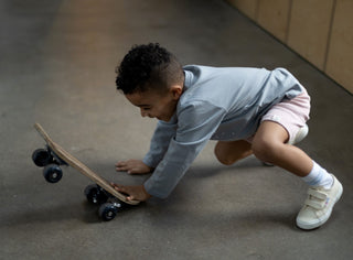 Child model playing with a wooden skateboard wearing Aneby shorts and top