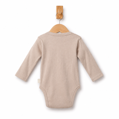 A long-sleeve baby bodysuit in a soft, light beige fabric, shown from the back hanging on a wooden hanger against a clean white background.