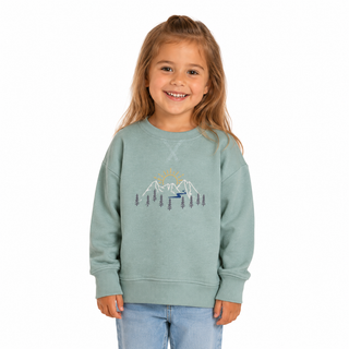 Child wearing a light green sweatshirt with a mountain design on a white background