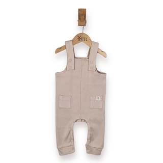 A baby romper in a light beige rib cotton fabric, hanging on a wooden hanger with a wooden peg against a plain white background.