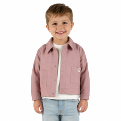 A young boy smiling, wearing a dusty pink button-up jacket over a white t-shirt and light blue jeans, photographed against a solid white background.
