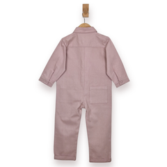 A dusty pink cotton baby jumpsuit shown from the back, hanging on a wooden hanger against a plain white background.