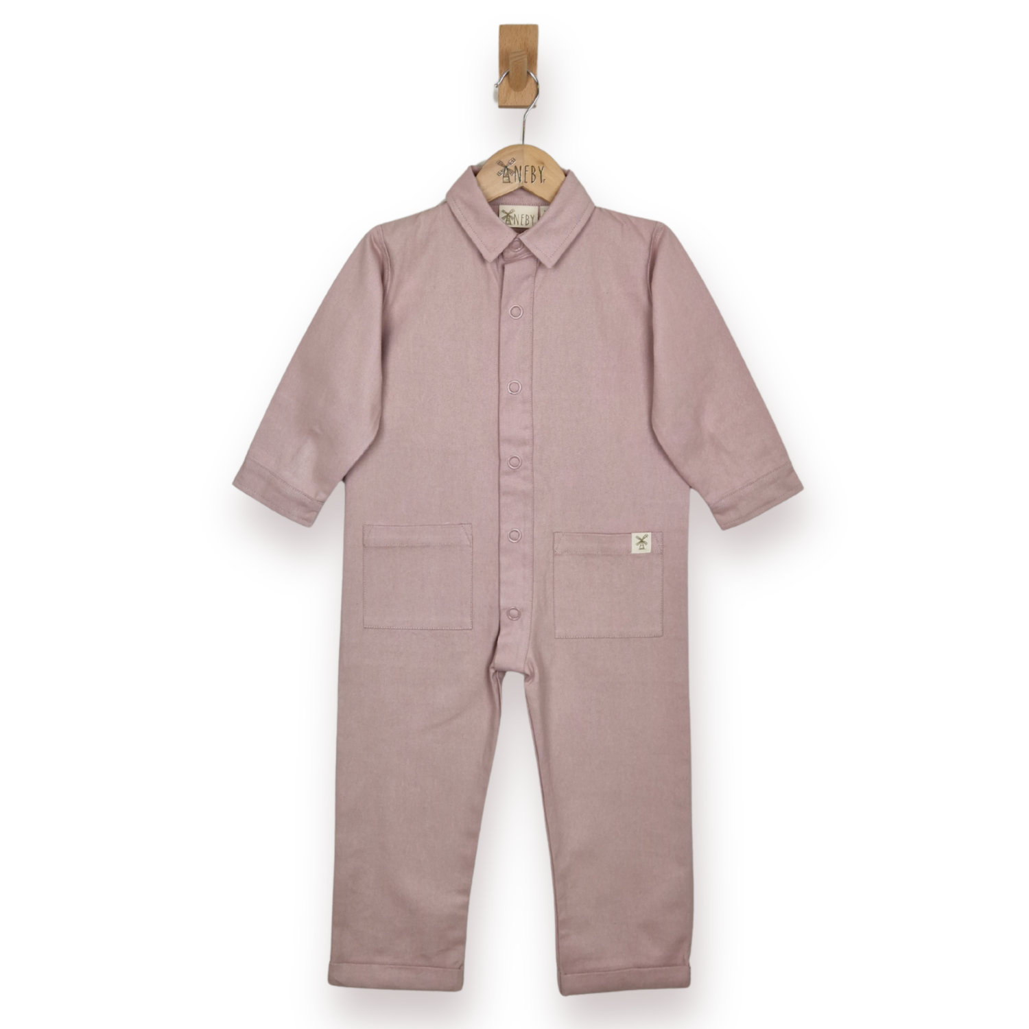 A dusty pink child's jumpsuit hanging on a wooden hanger against a plain white background. The boilersuit features a button-up front, a shirt collar, and two front patch pockets.