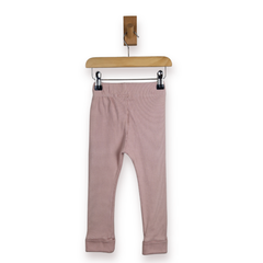 A pair of pink children's leggings hanging from a wooden hanger with black clips against a plain white background, rear shot. 