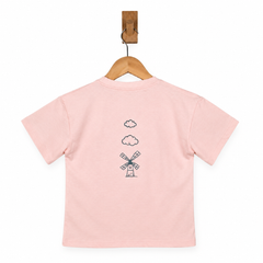 Pink t-shirt with a windmill design on a wooden hanger against a white background