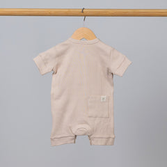 Back view of short sleeve playsuit in beige oat on wooden hanging rail