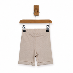 Beige ribbed knit shorts with rolled cuffs, hanging from a wooden hanger with black clips against a white background.